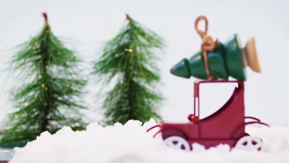 Toy car carrying christmas tree on fake snow