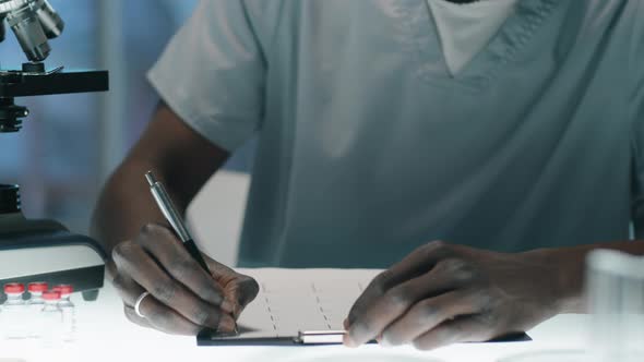 Black Lab Worker Taking Notes and Using Microscope