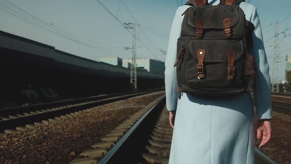 girl Sunny day with backpack on her back is walking along railway tracks.