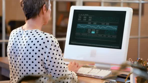 Rear view of female executive working on computer at desk