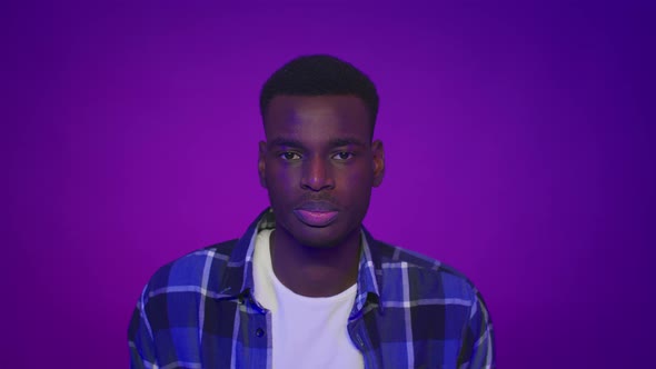 Serious African American Man Looking At Camera Over Purple Background