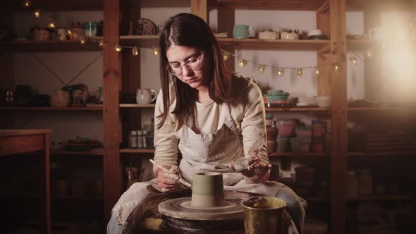 Young Woman Potter Coloring the Wet Clay Pot in Green Color Using a Brush