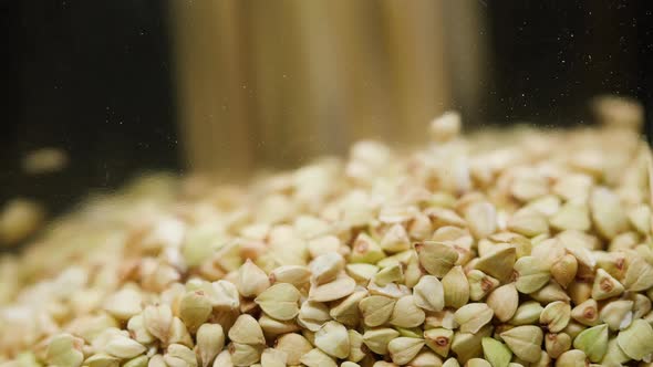 Closeup of Falling Down Green Buckwheat Into Glass Jar on Black Background