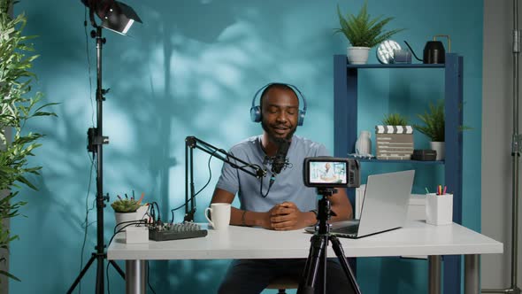 Cheerful Vlogger Waving at Camera While Recording Podcast