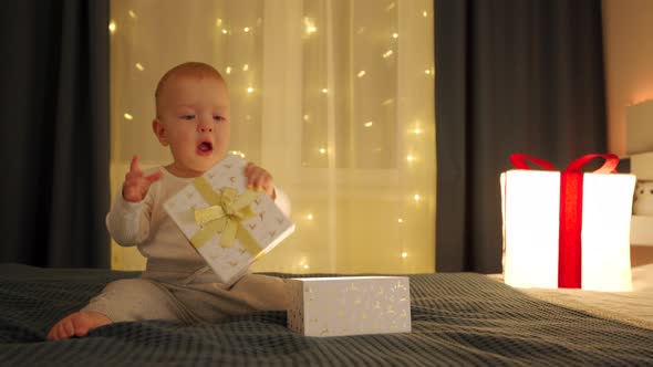 Cute Kid Opening a Gift Box and Taking Out Some Kind of Present From It