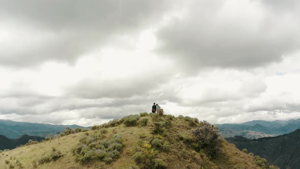 Ascending tracking shot of couple standing on peak of mountain and enjoying volcano crater lake view