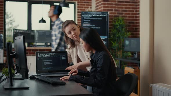 Team of Software Developers Comparing Source Codes Running on Laptop Screen and Computer Monitor