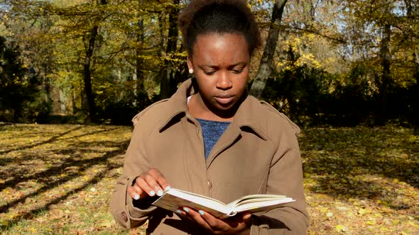 Young African Happy Girl Stands in the Woods, Observes Landscape and with Interest Reads a Book