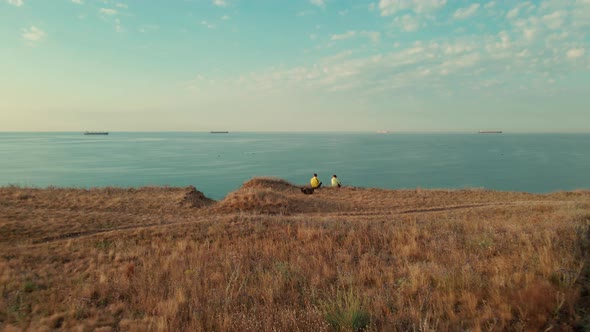 Two Travelers with Dog Sitting on the Edge of Cliff and Overlooking the Black Sea