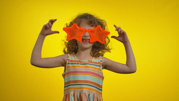 Curly Girl in Funny Huge Star Glasses with a Charming Toothless Smile is Dancing