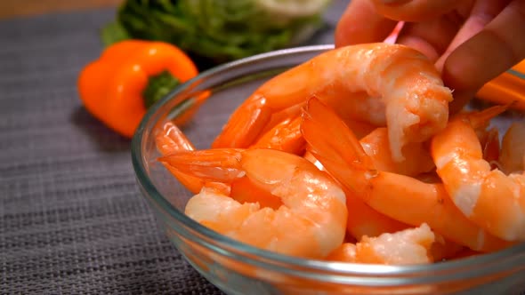 Closeup of a Hand Laying a Prepared Shrimp in a Glass Bowl