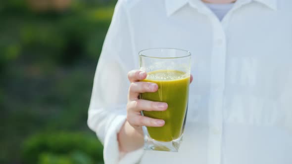 The Girl Holds a Glass of Green Cocktail. Healthy Eating Concept