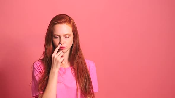 Redhaired Ginger Woman in Pink Studio Background Picks His Nose Finger