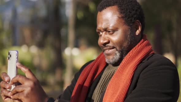 Smiling African man making photo of nature in park