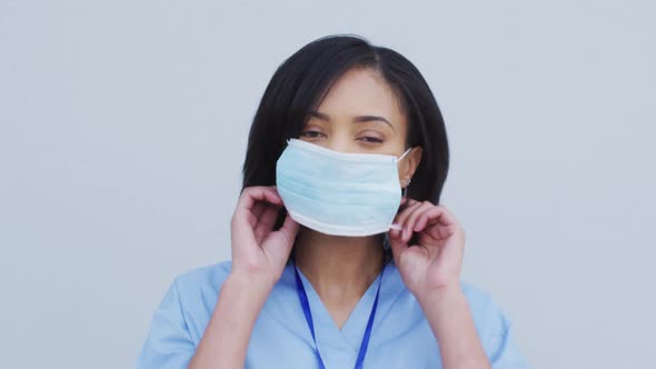 Portrait of Female health worker wearing face mask against white background