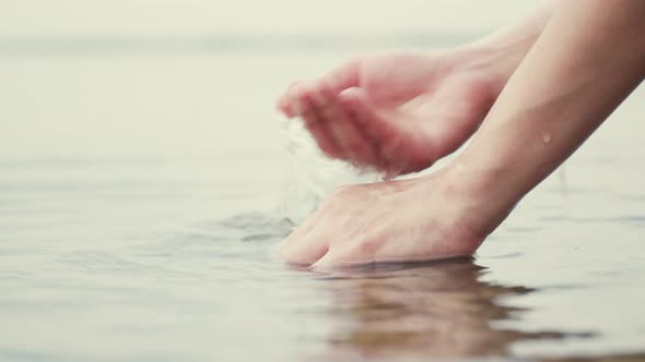 Close up hands washing in the forest river or lake.