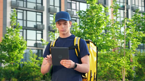 Portrait Delivery Man Courier with Thermal Backpack Uses Tablet Confirm Order