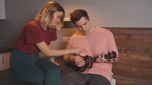 Attractive Young Couple Learning To Play the Guitar, Self-taught People Watching Guitar Lessons