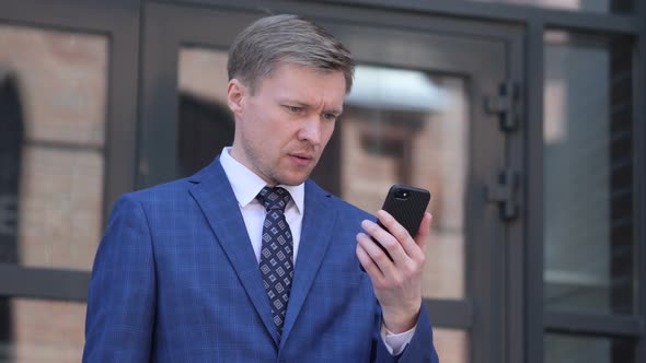 Wondering Businessman in Shock while using Smartphone