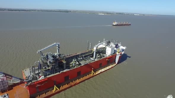 Aerial view of cargo ship arriving at the port with the help of tugs.