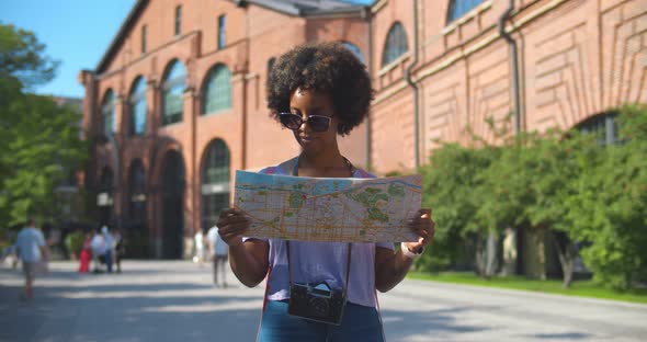 Cheerful Afro Woman Wanderer Searching Direction on Location Map Traveling Abroad in Summer