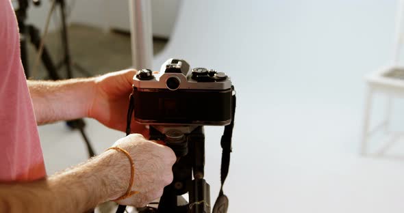 Male photographer adjusting camera in photo studio