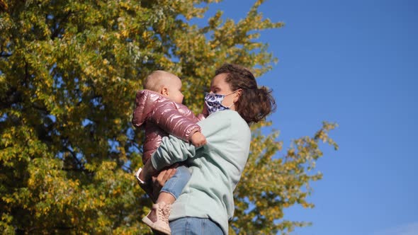 Caucasian Mom in a Face Mask Holds Her Daughter