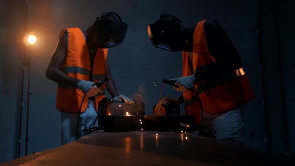 Two black African-Americans work with welding machines and weld metal structures