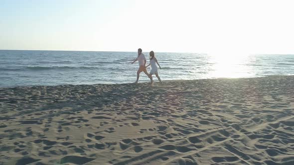 Aerial View of Couple Having Fun Running Along the Beach Near the Water