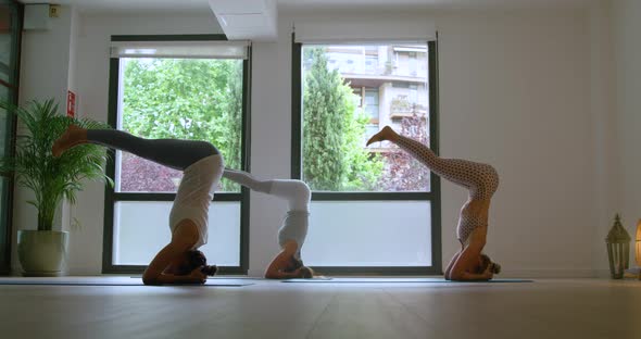 Group of female athletes performing Supported Headstand IV yoga asana