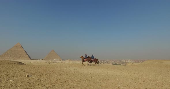 Woman riding horse with local man in front of Giza pyramids