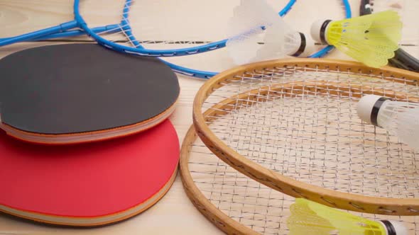 Badminton and Ping Pong Rackets on Wooden Background Close Up