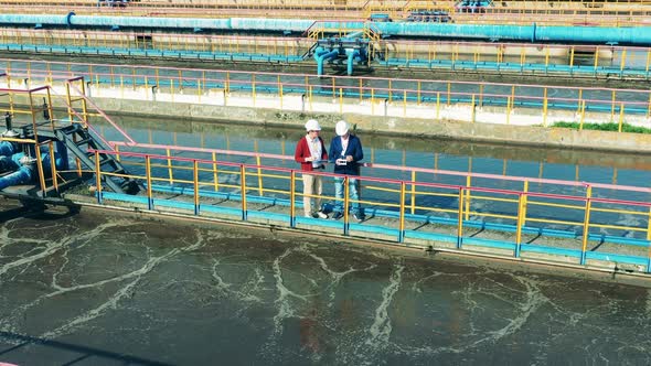 Male Workers on the Bridge at the Wastewaters Cleaning Site