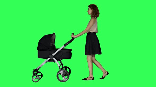A mother walking with a stroller, looking around and at her baby, smiling, over a green screen. 4K