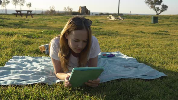 Female Using Tablet in the Park with Sea at Horizon