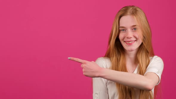 A Young Red Haired Woman with Freckles is Pointing to the Right and Smile