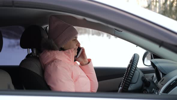 Female Talking on Phone in Her Car in Winter Day