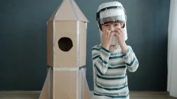 Slow Motion Portrait of Small Kid in Cosmonaut Costume Smiling Looking at Camera Against Rocket