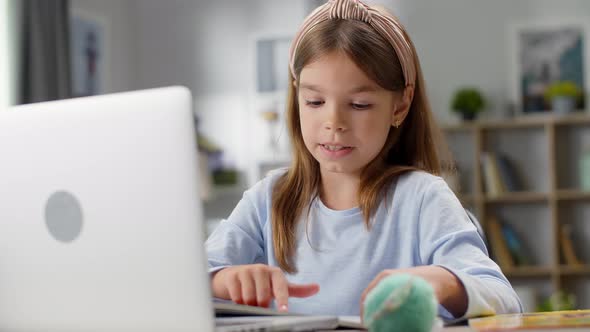 Beautiful Little Girl Studying at Home Using Laptop