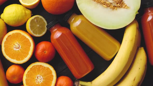 Yellow and Orange Fruits and Botteled Juices Placed on Black Wooden Background