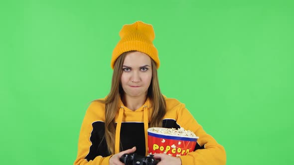 Portrait of Modern Girl in Yellow Hat with Popcorn Is Playing a Video Game Using a Wireless