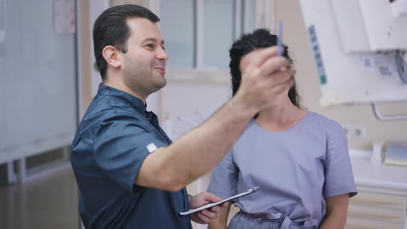 Positive Middle Eastern Dentist and Caucasian Assistant Talking in Slow Motion Looking at Screen