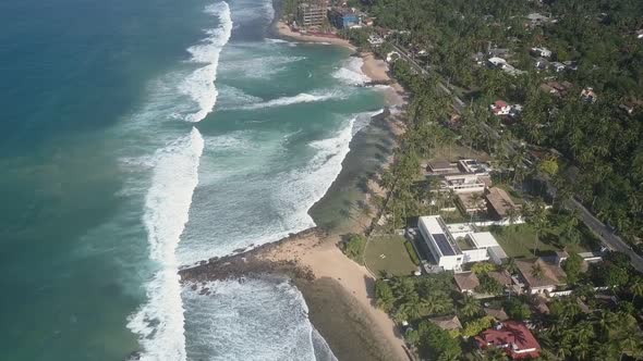 Foaming Ocean Waves Roll on Island Coastline with Buildings