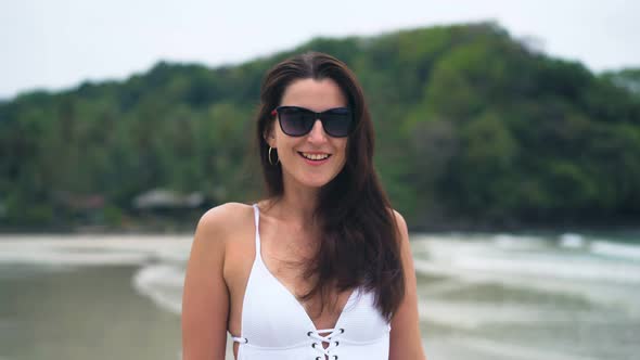 Beautiful Woman in a White Swimsuit Walking on the Beach