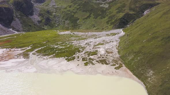 Mountain lake of beige or milky color in a valley