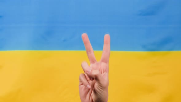 Hand in Victory Symbol with Ukrainian Flag for Background