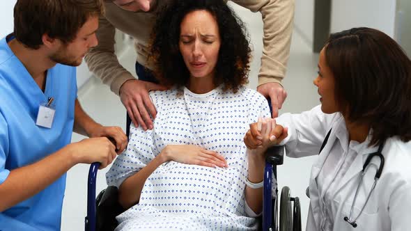 Doctors and man comforting pregnant woman in corridor