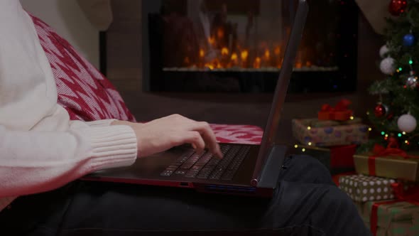 A man's hands closeup home working on a laptop during winter holidays.