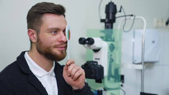 Handsome male checks vision in ophthalmological clinic. Optometrist trial frame. Healthcare concept.