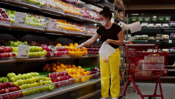 Young Woman in a Mask From a Coronavirus Epidemic is Standing in the Grocery Department of a